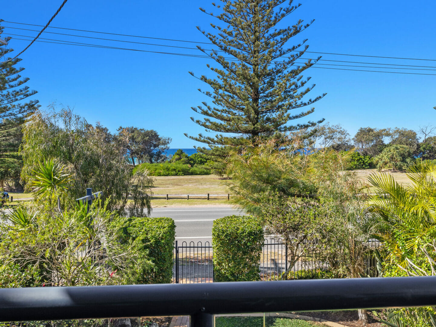 Balcony handrail with view beyond of foreshore parkland, trees an ocean